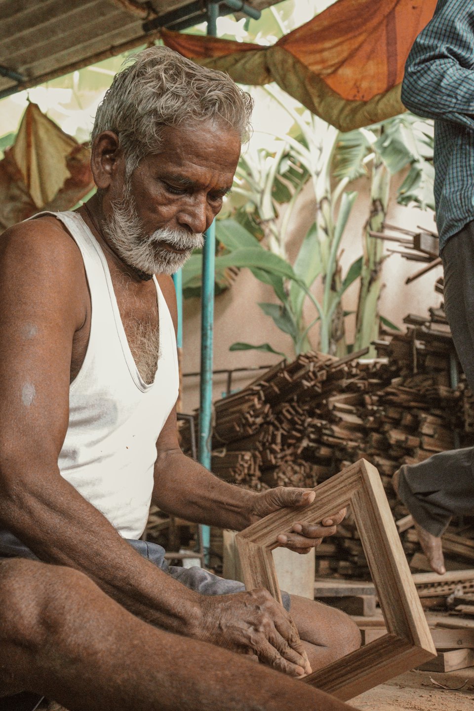 Craftsman assembling a wooden frame in an outdoor workshop.