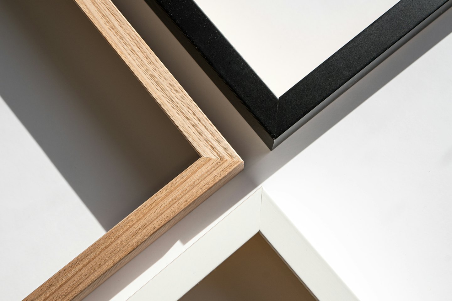 Three empty picture frames in wood, black, and white overlapping.