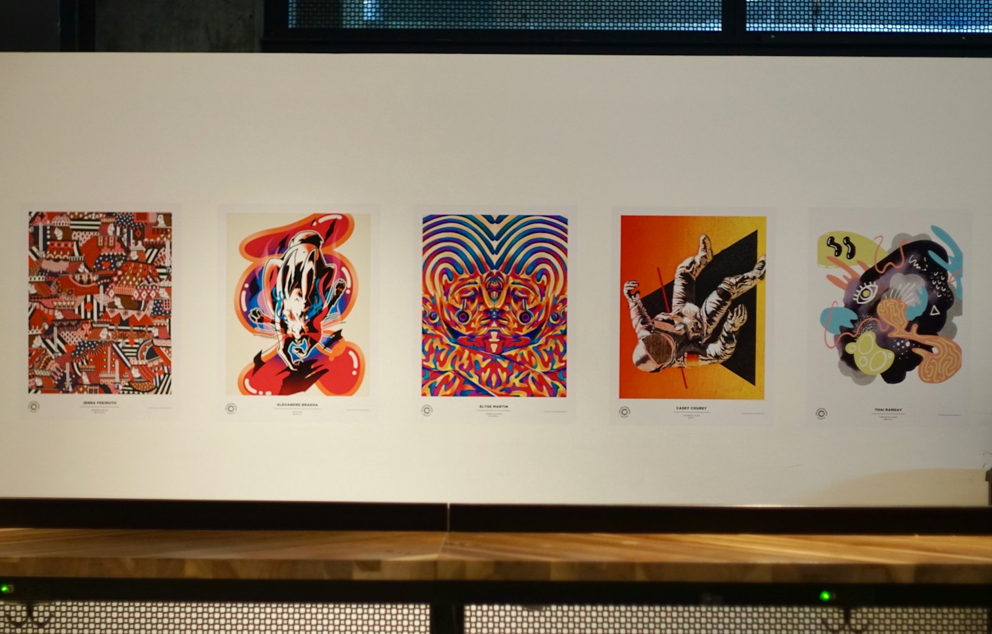 Five colorful graphic art prints displayed on a white wall.
