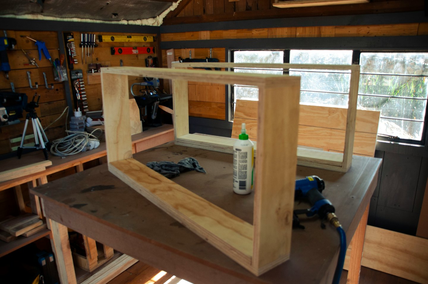 Two unfinished plywood frames on a workbench with tools.