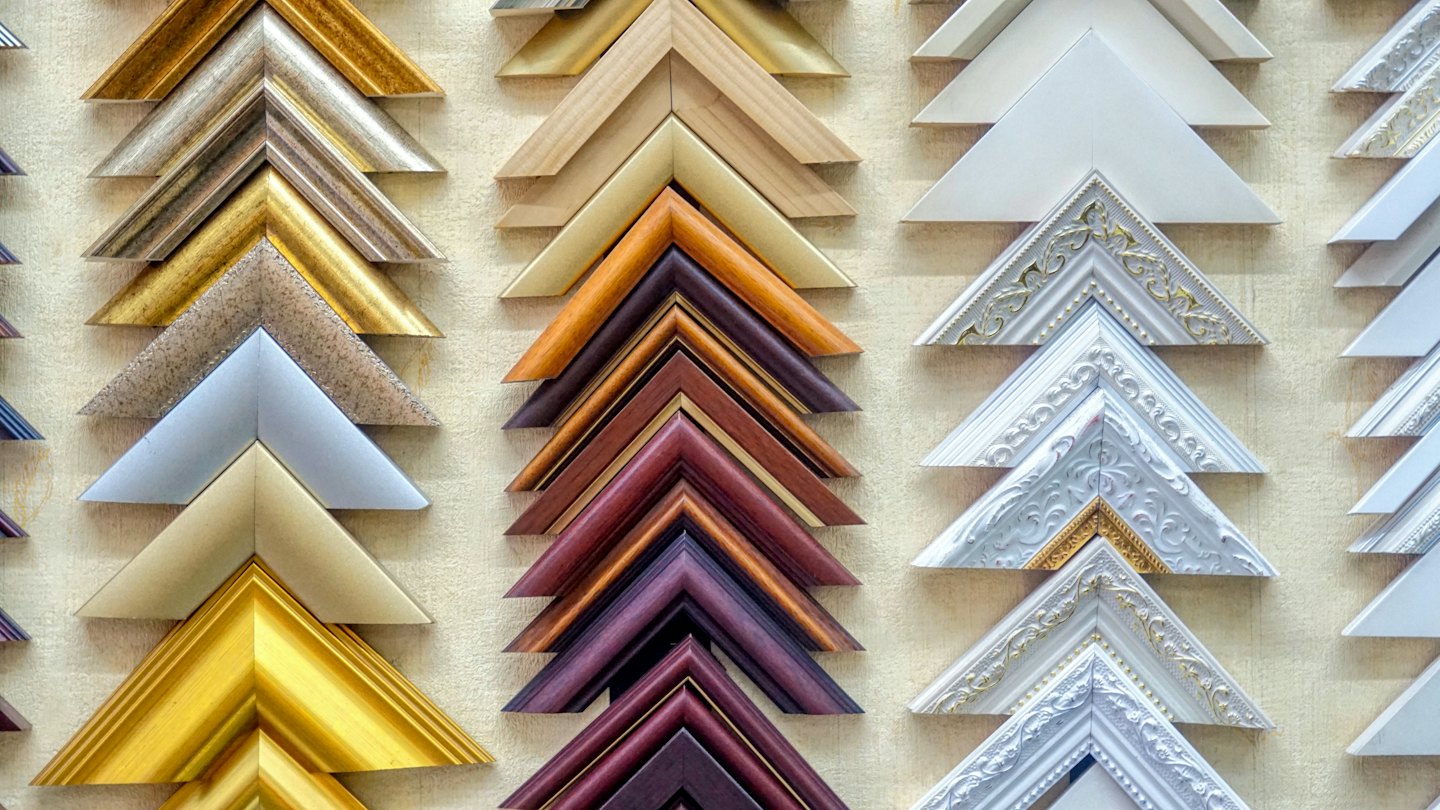 Various picture frame corner samples displayed on a wall.